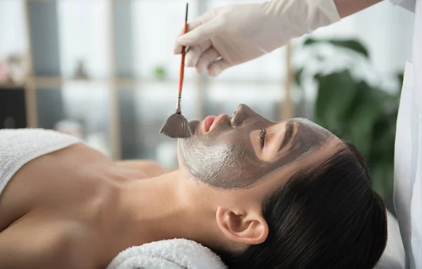Kosmetička, použití hlíny na ženský obličej — Stock fotografie