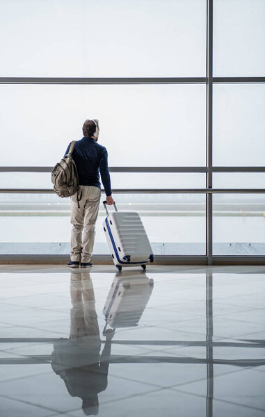 Thoughtful man listening to music at the airport