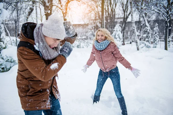 Huoleton nuori mies ja nainen pelaa lumipalloja — kuvapankkivalokuva