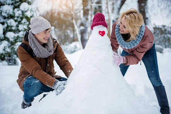 Счастливые мужчина и женщина делают фигуру из снега — стоковое фото