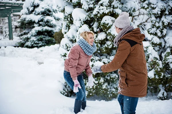 Беззаботная любящая пара играет в снежки в парке — стоковое фото