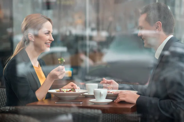 Cheerful partners tasting dish at table — Stock Photo, Image