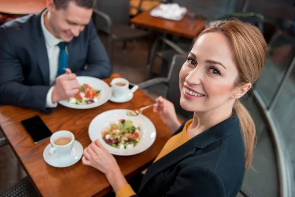 Cheerful colleagues tasting dish at desk — Stock Photo, Image