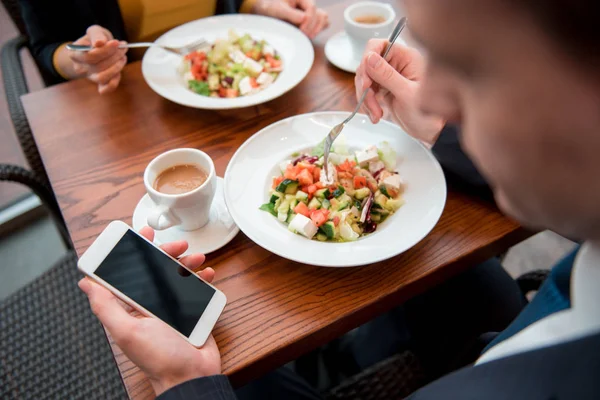 Männchen hält mobil und isst Salat — Stockfoto
