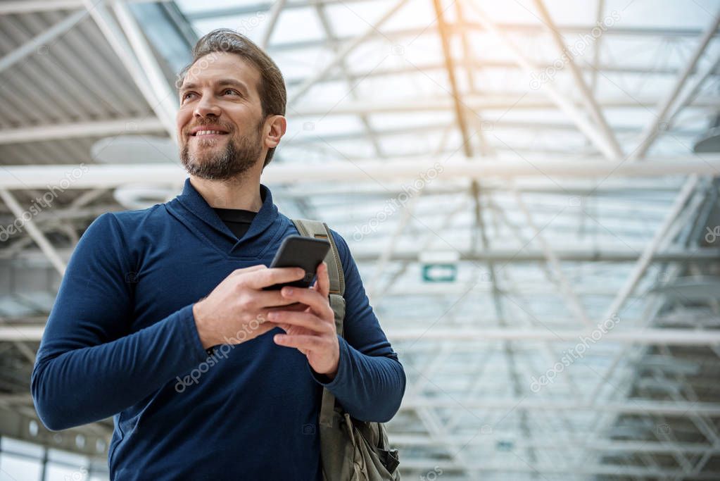 Glad male person using phone in the airfield