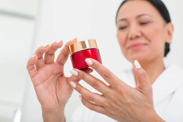 Mujer feliz examinando la instrucción de los cosméticos en el centro de bienestar —  Fotos de Stock