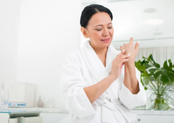 Vyrovnaná žena pomocí kosmetiky ve wellness centru — Stock fotografie
