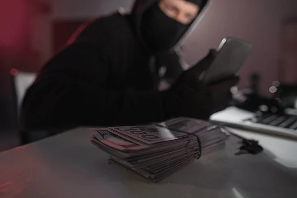 Bargeld auf Schreibtisch neben Hacker im Zimmer — Stockfoto