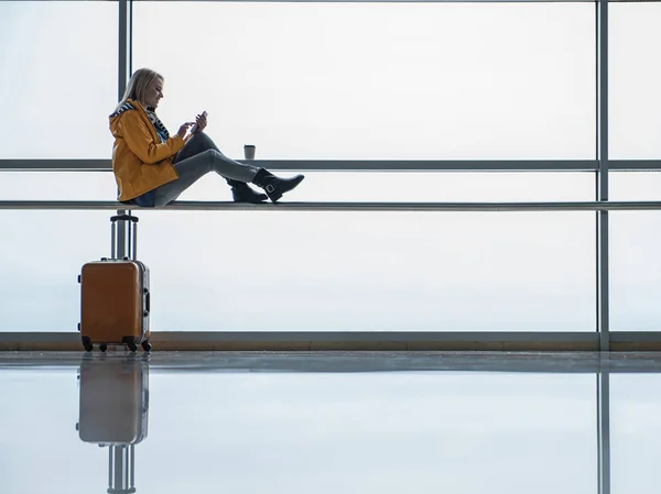 Optimistisch vrouwelijke toeristische is het gebruik van smartphone bij terminal lounge — Stockfoto