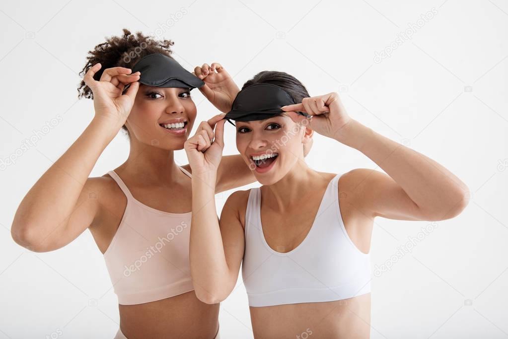 Joyful fit ladies putting on sleeping masks