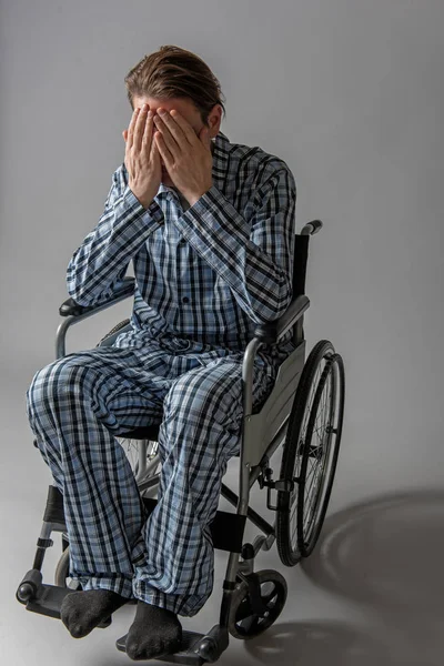 Pessimista storpio in sedia che si copre il viso con le mani — Foto Stock