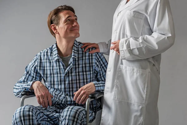 Uomo disabile positivo in carrozza sostenuto dal lavoratore ospedaliero — Foto Stock