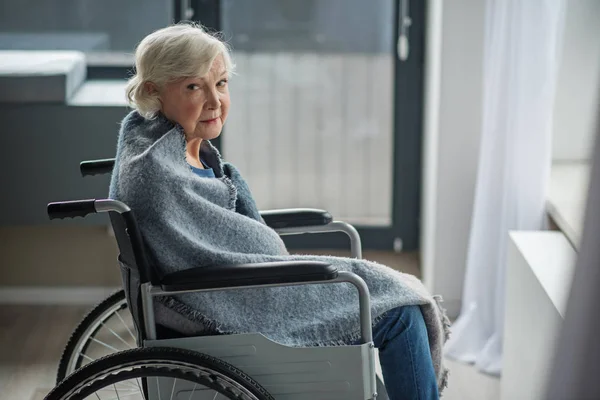 Moody velha sentada em cadeira de rodas no quarto — Fotografia de Stock