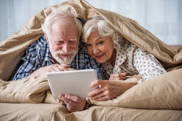 Glad pensionistas navegando por Internet en el dormitorio —  Fotos de Stock