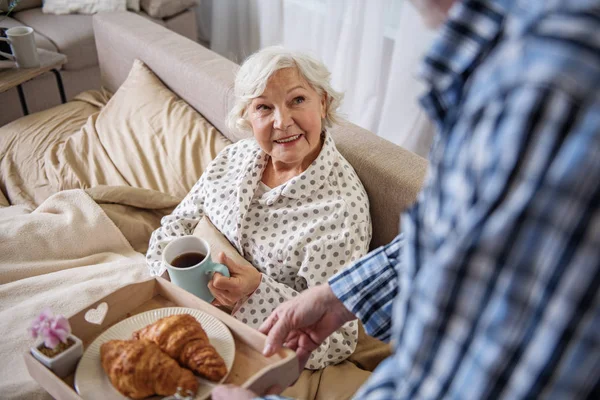 Tranquilo hombre mayor trayendo el desayuno a la mujer en la cama —  Fotos de Stock