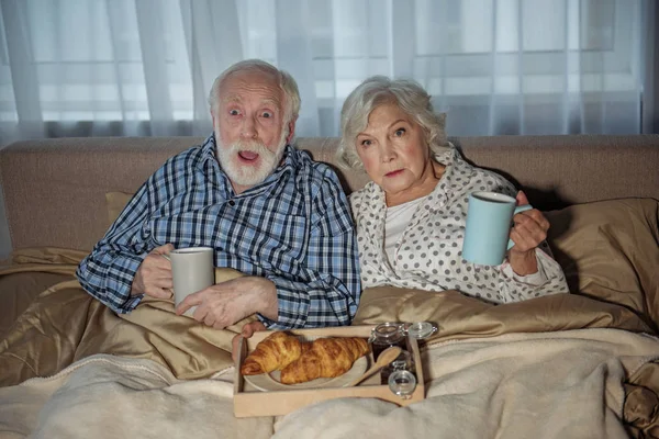Pensionistas horrorizados viendo televisión en casa — Foto de Stock