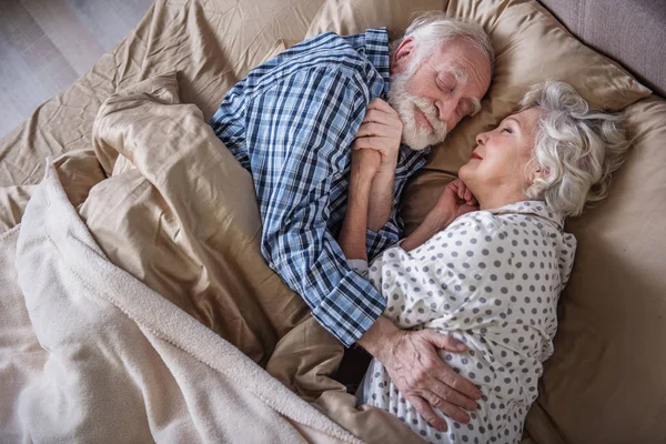 Feliz casal de idosos dormindo e abraçando dentro de casa — Fotografia de Stock