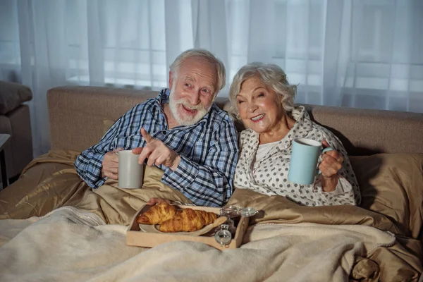 Feliz pareja de ancianos comiendo en el dormitorio — Foto de Stock