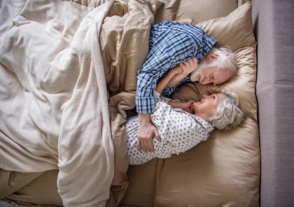 Pensionistas tranquilos abrazando y acostados en la cama — Foto de Stock