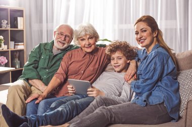 Cihaz ile birlikte oturan aile gülen