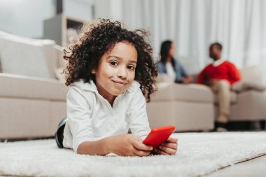 Memnun çocuk smartphone ile halı üzerinde rahatlatıcı