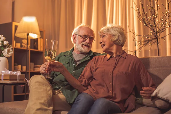 Счастливая зрелая пара пьет шампанское на диване — стоковое фото