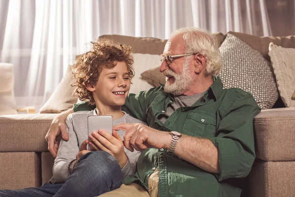 Улыбающийся дедушка и телефон для детей — стоковое фото