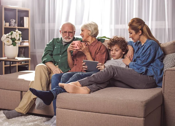 Familiares alegres relajarse con gadget en el sofá — Foto de Stock