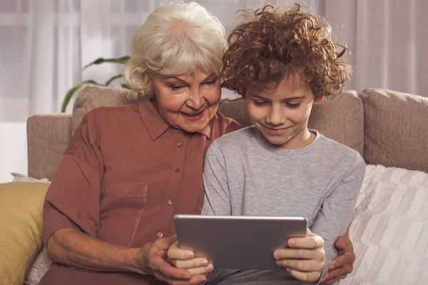 Fröhliche Großmutter und Junge schauen auf Gadget — Stockfoto