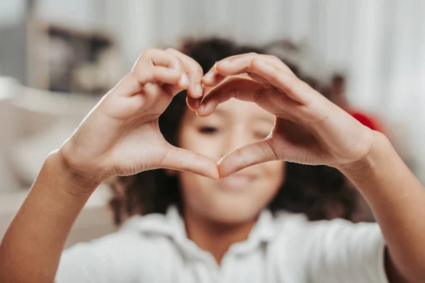 Niño disfrutado espiando a través de los dedos en forma de corazón — Foto de Stock