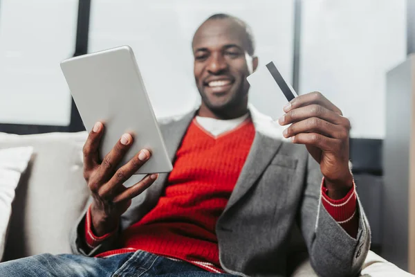 Мужчина отдыхает с планшетом и банковской картой в руках — стоковое фото