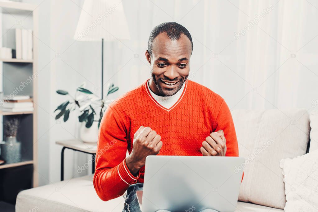 Smiling man jubilating in front of laptop