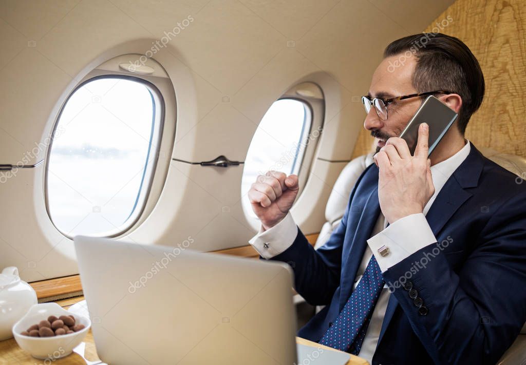 Pleased middle aged man talking by phone