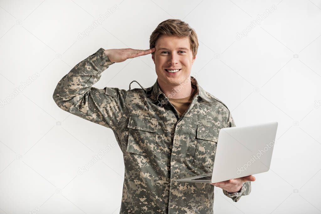 Glad military young man using laptop