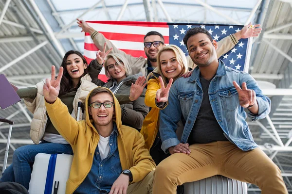 Turistas alegres demonstrando bandeira americana no terminal — Fotografia de Stock