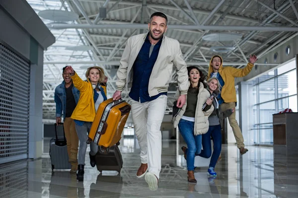 Compañeros felices con las carreras de equipaje en el aeropuerto —  Fotos de Stock