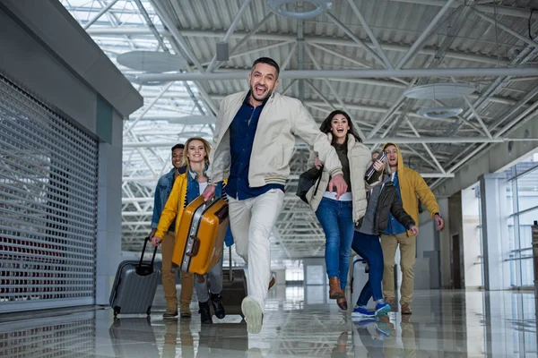 Lächelnde Freunde mit Taschen, die sich für einen Flug beeilen — Stockfoto