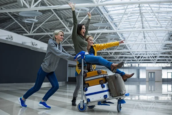 Amigos contentos divirtiéndose con el carrito de equipaje —  Fotos de Stock