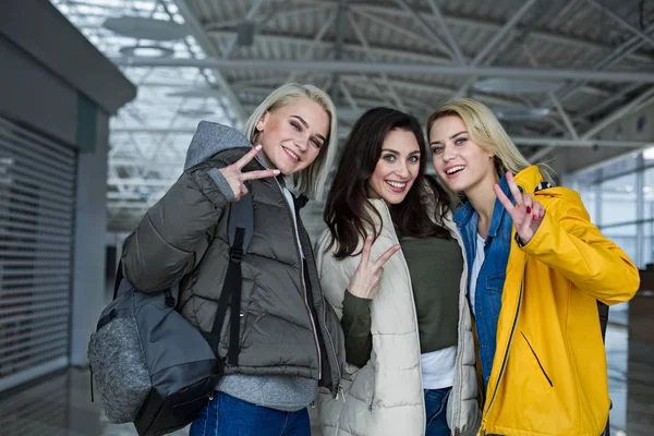 Mesdames souriantes debout dans le terminal avec des sacs à dos — Photo