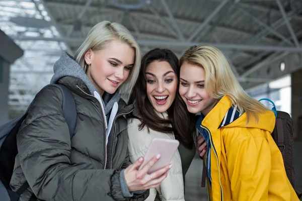 Groupe de filles joyeuses à l'aéroport se concentrant sur le téléphone portable — Photo