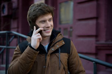 Neşeli adam smartphone ile ayakta ve arkadaşlarıma çağrı