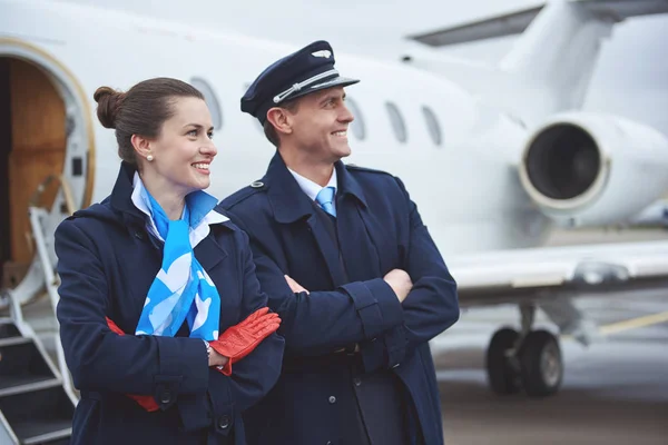 Glad-flygvärdinna och pilot lokalisering nära flygplan — Stockfoto