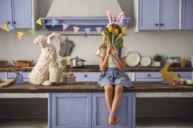 Buket ile mutfağında oturan küçük kız