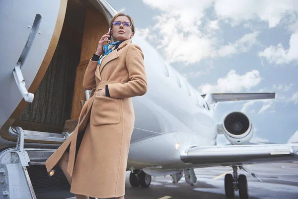 Lugn affärskvinna talar av mobil nära flygplan — Stockfoto