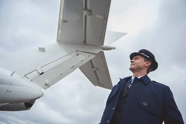 Strahlender Pilot beobachtet am Heck des Flugzeugs — Stockfoto