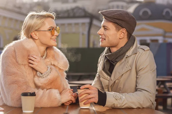 Happy romantic couple on date is talking in cafe outdoors