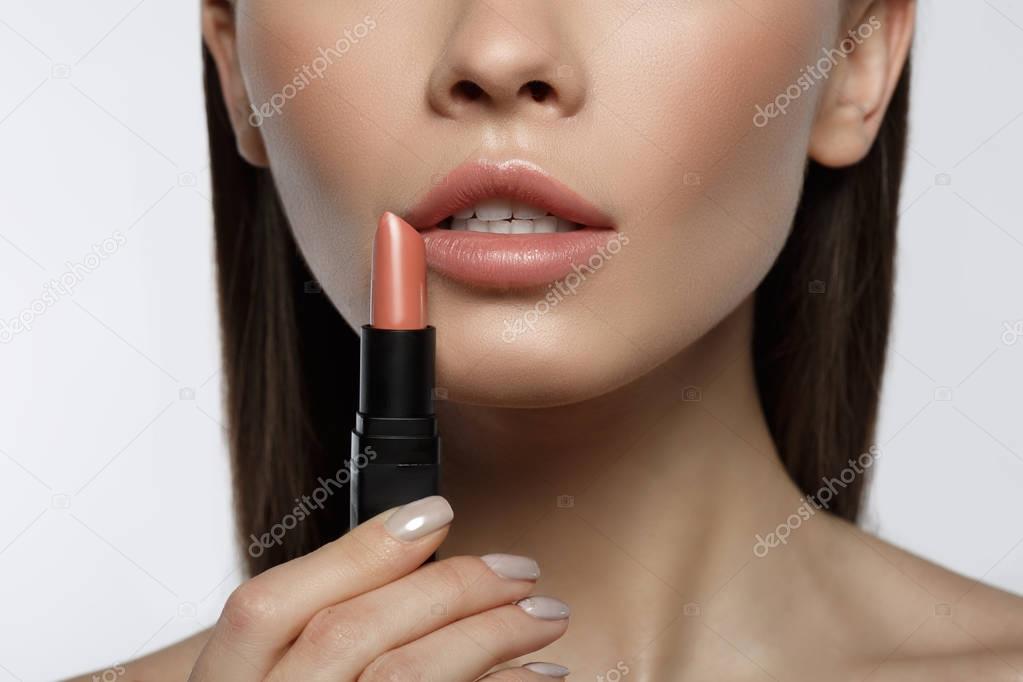 Sensual young woman applying color on lips