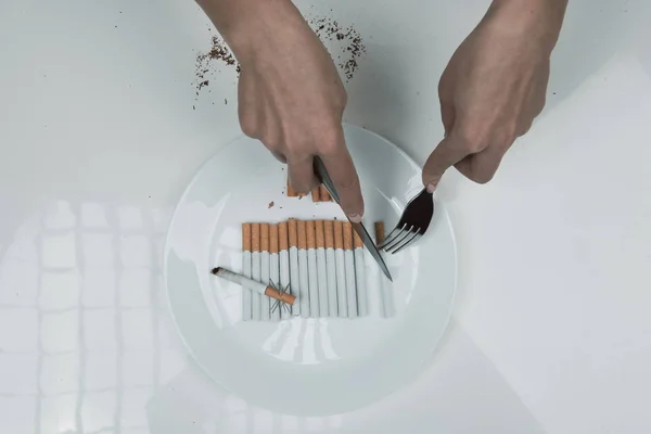 Manos femeninas bisecando cigarrillo con cubiertos — Foto de Stock