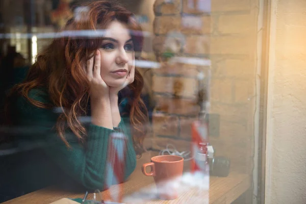 Nadenkend meisje zit in de buurt van venster in cafetaria — Stockfoto