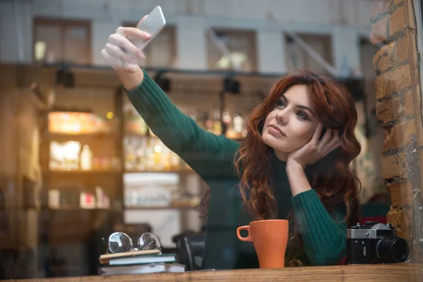 Pretty girl taking photo of herself on phone in cafeteria — Stock Photo, Image